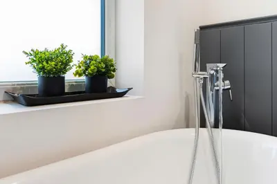a bath tub in a bathroom with plants on a window sill at Spacious 4B home, great for contractors and families in Wigan
