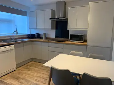 a kitchen with white cabinets and a table with chairs at Seaside Serenity in Lytham St Annes