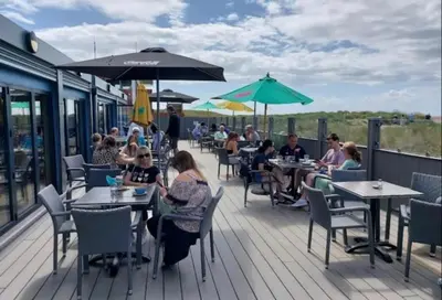 a group of people sitting at tables on a deck at Seaside Serenity in Lytham St Annes