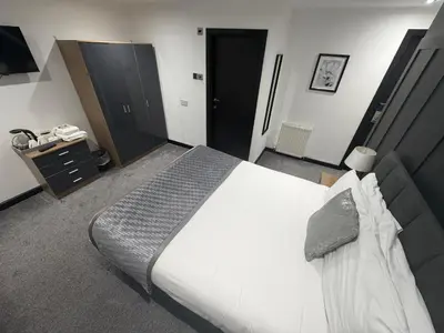 a bedroom with a large white bed and a dresser at Woodhouse Hotel Blackpool Promenade in Blackpool