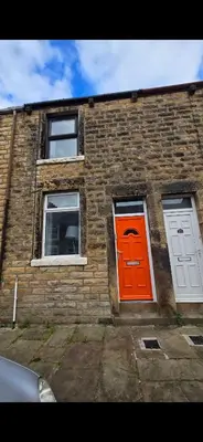 a brick building with an orange door and two windows at Cozy Stays Lancaster in Lancaster