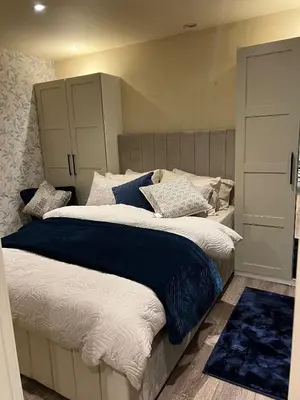 a bedroom with a large bed with blue and white pillows at 2 bedroom self catering detached outhouse with garden area in Preston