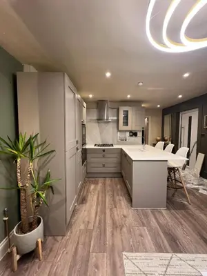 a kitchen with white cabinets and a table with a plant at 2 bedroom self catering detached outhouse with garden area in Preston