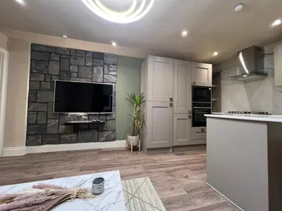 a kitchen with a flat screen tv on a stone wall at 2 bedroom self catering detached outhouse with garden area in Preston
