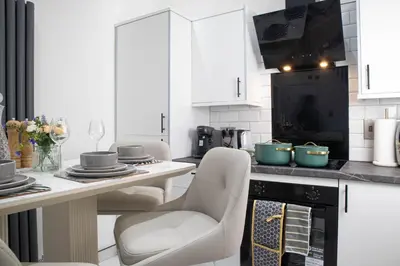 a kitchen with white cabinets and a table with chairs at Stylish Preston Home 3 Beds Sleeps 6 in Preston