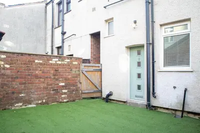 a cat sitting in a yard next to a brick wall at Stylish Preston Home 3 Beds Sleeps 6 in Preston