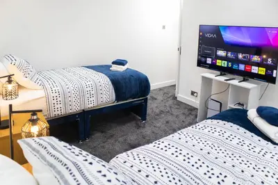 a room with two beds and a flat screen tv at Stylish Preston Home 3 Beds Sleeps 6 in Preston