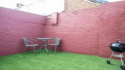 a red wall with two chairs and a table and a grill at Stylish Preston Home 3 Beds Sleeps 6 in Preston