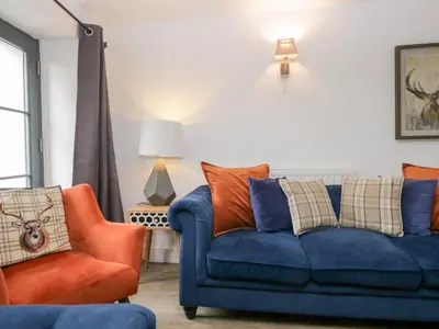 a living room with a blue couch and an orange chair at No 2 The Flags in Grange Over Sands