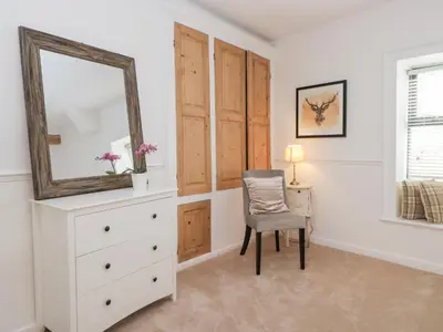 a bedroom with a dresser and a mirror and a chair at No 2 The Flags in Grange Over Sands