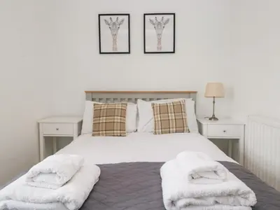 a bedroom with a white bed with two towels on it at No 2 The Flags in Grange Over Sands