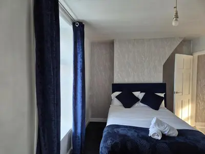 a bedroom with a bed with blue curtains at Peaceful Home in Hermitage Street Rishton in Rishton
