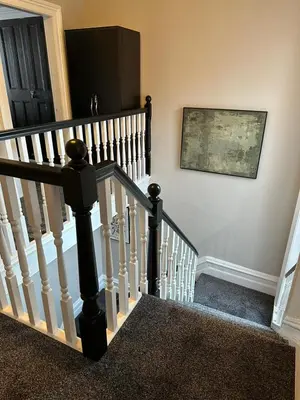 a staircase with white railings and a painting on the wall at A Comfy Stay Close to City-Centre in Preston