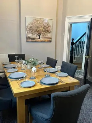 a wooden table with plates and glasses on it at A Comfy Stay Close to City-Centre in Preston