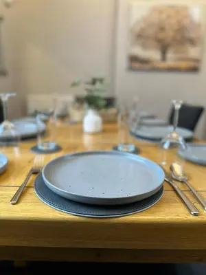 a wooden table with a plate and utensils on it at A Comfy Stay Close to City-Centre in Preston