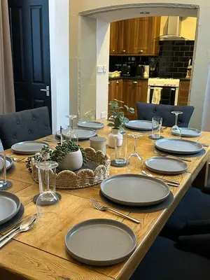 a wooden table with plates and glasses on it at A Comfy Stay Close to City-Centre in Preston
