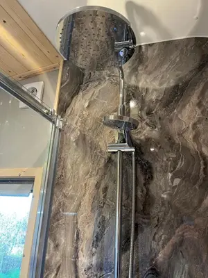 a shower in a bathroom with a stone wall at Mill House Farm Pods- Kingfisher in Pilling