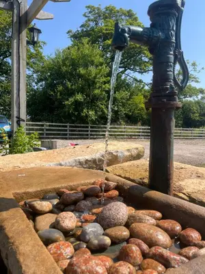a water fountain with rocks in a pond at Mill House Farm Pods- Kingfisher in Pilling