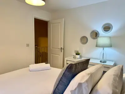 a bedroom with a bed and a table with a lamp at 4 Bed - Parking - Fast WiFi - Desk - M6 M61 links - Pets in Leyland