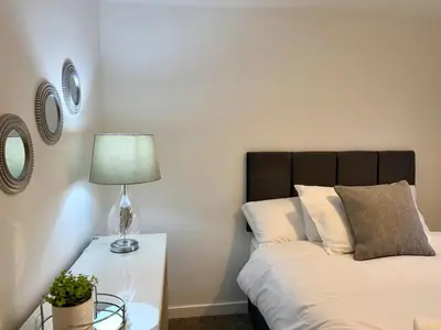 a bedroom with a bed and a lamp on a table at 4 Bed - Parking - Fast WiFi - Desk - M6 M61 links - Pets in Leyland