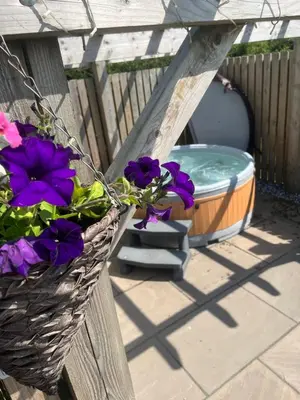 a basket of flowers on a fence with a bath tub at Mill House Farm Pods - Mallard View in Pilling