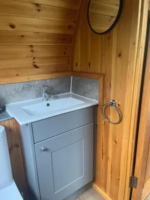 a bathroom with a white sink in a wooden wall at Mill House Farm Pods - Mallard View in Pilling