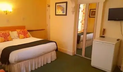 a hotel room with a bed and a television at MyRoomz Tudor Rose Original in Blackpool