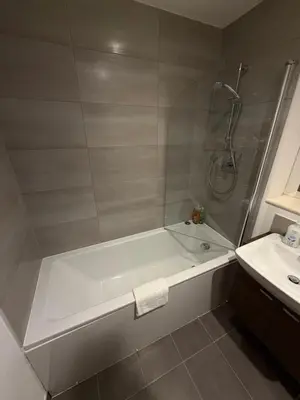 a bathroom with a bath tub and a sink at Stunning City View Studio Apartment by StaySavvy Accommodation in Liverpool