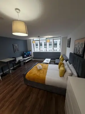 a bedroom with a large bed and a couch at Stunning City View Studio Apartment by StaySavvy Accommodation in Liverpool