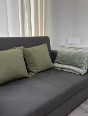 a gray couch with pillows on it in a living room at Cosy Double and Triple Bedrooms 5 minutes from Anfield Stadium in Liverpool