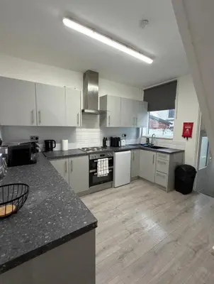 a large kitchen with white cabinets and a counter top at Cosy Double and Triple Bedrooms 5 minutes from Anfield Stadium in Liverpool
