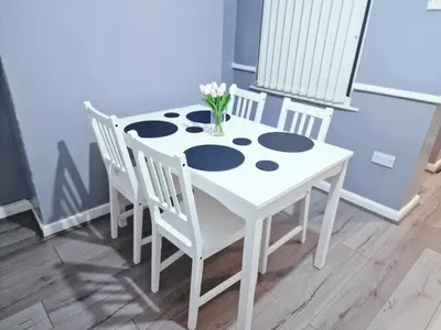 a white table with chairs and a vase of flowers on it at Stylish Modern Home comfy setting by Everton Park in Liverpool