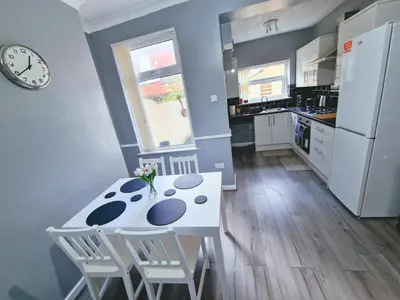 a kitchen with a white table and chairs and a clock at Stylish Modern Home comfy setting by Everton Park in Liverpool