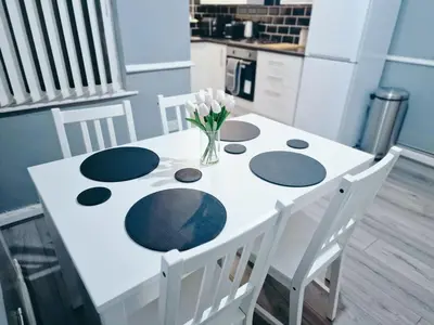 a white table with a vase of flowers on it at Stylish Modern Home comfy setting by Everton Park in Liverpool