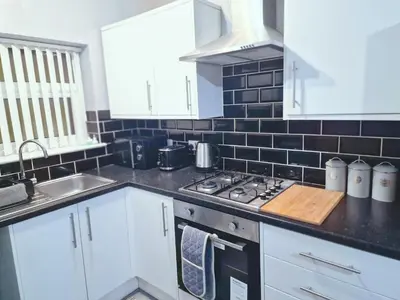 a kitchen with white cabinets and a stove and a sink at Stylish Modern Home comfy setting by Everton Park in Liverpool