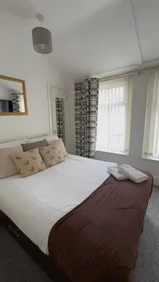 a large white bed in a room with windows at No 34 Vance Road in Blackpool
