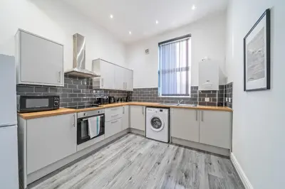 a kitchen with white cabinets and a washer and dryer at Latimer Flat 1 - Spacious 2-Bed Apt - Sleeps 7 - Ground Flr in Liverpool