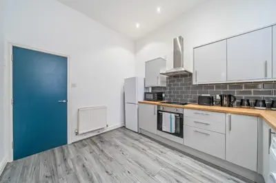 a kitchen with white cabinets and a blue door at Latimer Flat 1 - Spacious 2-Bed Apt - Sleeps 7 - Ground Flr in Liverpool