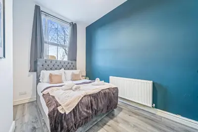a bedroom with a large bed with a blue wall at Latimer Flat 1 - Spacious 2-Bed Apt - Sleeps 7 - Ground Flr in Liverpool