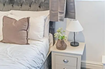 a bed with white pillows and a lamp on a night stand at Latimer Flat 1 - Spacious 2-Bed Apt - Sleeps 7 - Ground Flr in Liverpool