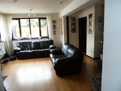 a living room with a black leather couch and a window at smithy lodge guest house in Leyland