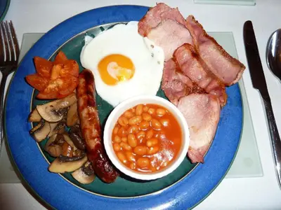 a blue plate with eggs sausage beans and bacon at smithy lodge guest house in Leyland