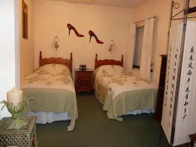 two beds in a room with red shoes on the wall at smithy lodge guest house in Leyland