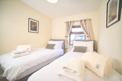two beds in a room with a window at Modern Cosy 2-Bed Terrace with Private Garden in Eccleston