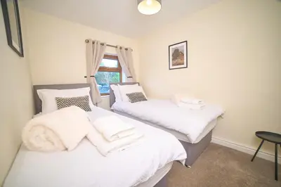 two twin beds in a room with a window at Modern Cosy 2-Bed Terrace with Private Garden in Eccleston