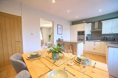 a kitchen with a wooden table with wine glasses on it at Modern Cosy 2-Bed Terrace with Private Garden in Eccleston