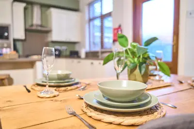 a wooden table with a bowl and plates on it at Modern Cosy 2-Bed Terrace with Private Garden in Eccleston