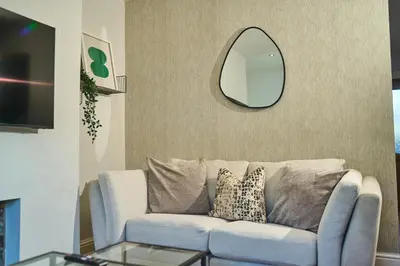 a living room with a blue couch and a mirror at Modern Cosy 2-Bed Terrace with Private Garden in Eccleston