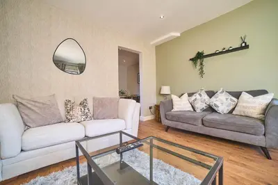 a living room with a couch and a mirror at Modern Cosy 2-Bed Terrace with Private Garden in Eccleston
