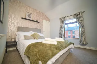 a bedroom with a large bed with towels on it at Modern Cosy 2-Bed Terrace with Private Garden in Eccleston